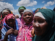 Grupo de mulheres deslocadas em Naminawe, próximo a Pemba, Moçambique, reunidas ao ar livre usando lenços coloridos, após fuga de ataques insurgentes.