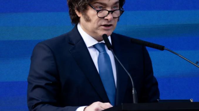 Milei fala ao microfone em um púlpito durante evento oficial.