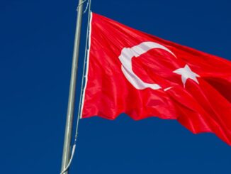 Bandeira da Turquia tremulando em mastro contra o céu azul.