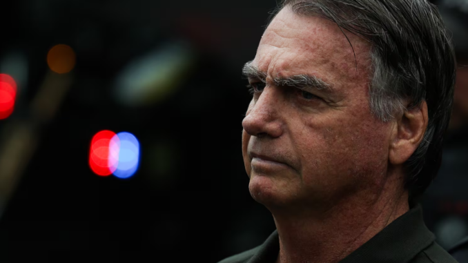 Ex-presidente Jair Bolsonaro com expressão séria em ambiente externo, com luzes desfocadas ao fundo