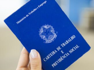 Mão segurando Carteira de Trabalho e Previdência Social do Brasil, símbolo do emprego formal.