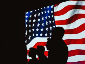 Silhuetas de pessoas diante da bandeira dos Estados Unidos simbolizando tensões políticas e relações internacionais