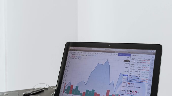 Investidor analisa gráfico de mercado financeiro em laptop, com variação de preços e volumes, em contexto de análise técnica do Ibovespa e contratos futuros