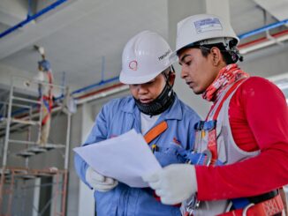 Trabalhadores da construção civil analisam projeto em obra durante atividade profissional