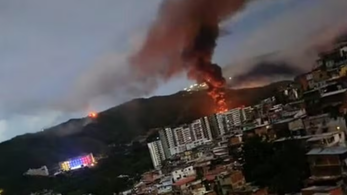 Explosão registrada em Fuerte Tiuna, a maior base militar da Venezuela, com coluna de fumaça e fogo visível sobre Caracas durante ofensiva militar.