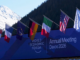 Fachada do World Economic Forum em Davos 2026 com bandeiras de países e cenário alpino ao fundo