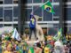 Manifestantes invadem a Praça dos Três Poderes em Brasília durante os ataques de 8 de janeiro de 2023, segurando bandeiras do Brasil em frente ao Congresso Nacional.